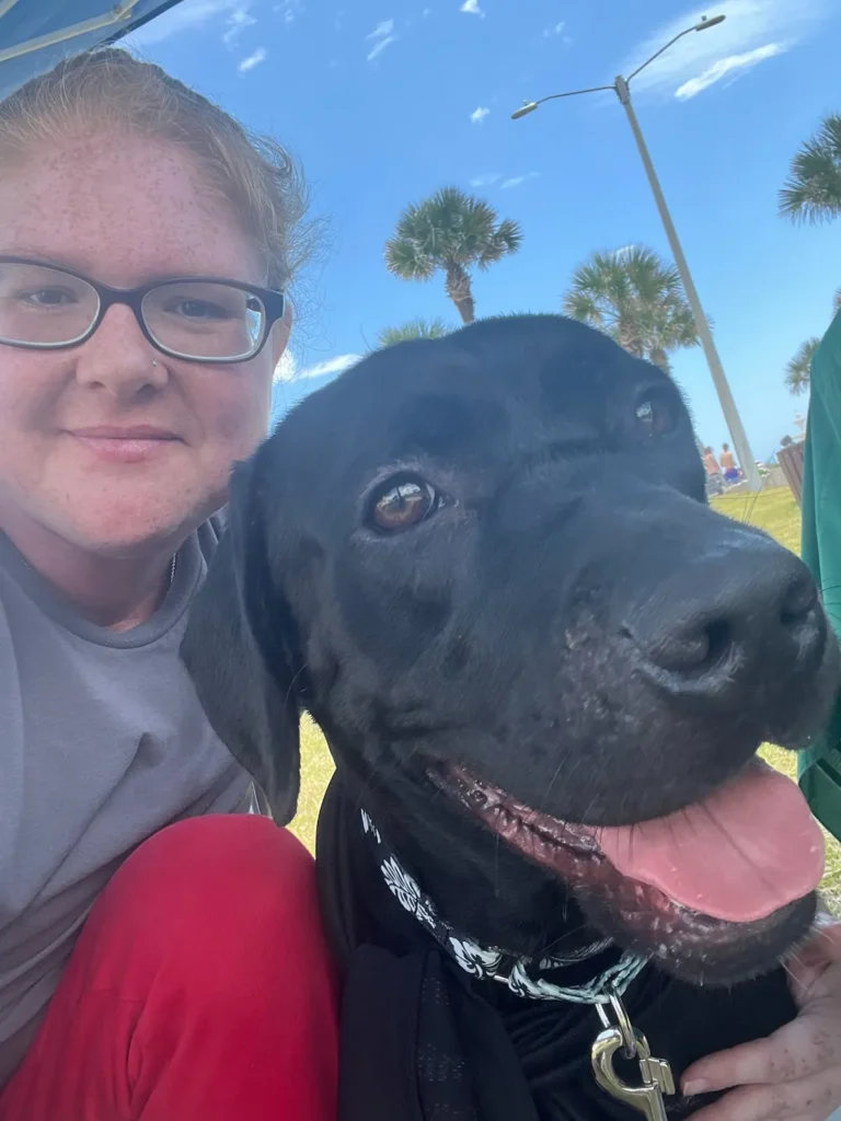 A woman taking a selfie with a black dog